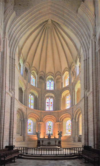 Abbaye de Cerisy-la-Forêt. À l’intérieur, la magnifique abside capte tous les regards. Avec ses quinze fenêtres romanes sur trois niveaux et ses coursières aux deux niveaux supérieurs, elle est unique. Les absides de Saint-Nicolas de Caen et de Saint-Gabriel sont édifiées suivant le même principe (sans collatéral) mais à une plus petite échelle. Le mur de l’abside est largement percé par ces quinze fenêtres, prodiguant une lumière abondante. Le mur de l’abside est en outre évidé par des coursières aux premier et second étages. À la hauteur du premier étage, les culots supportant l’arc de gloire, ajoutés à l’époque gothique, représentent des moines chantant et jouant d’instruments divers, ainsi que des anges. (Photo Rodolphe Corbin © Patrimoine Normand)