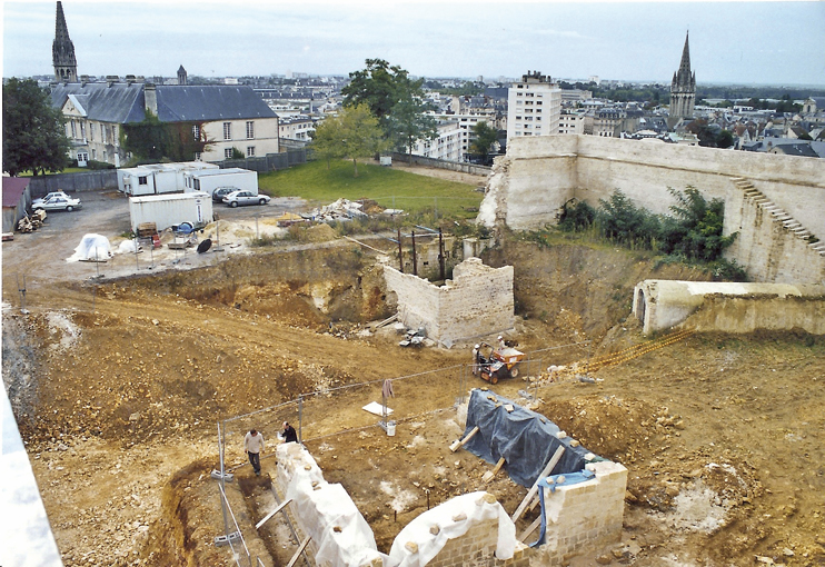 Le château de Caen en 2005, lors des fouilles qui ont précédé la construction de la salle du rempart. Les vestiges de la forge se situent au premier plan, les dessins de mors protégés par la bâche. (© Thierry Georges Leprévost) 