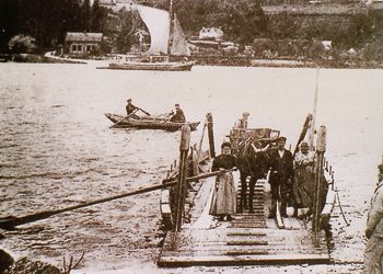 Le bac de Grand-Couronne vers 1910 (à droite un douanier, au fond un cotre de transport). (© Coll. Patrimoine Normand)