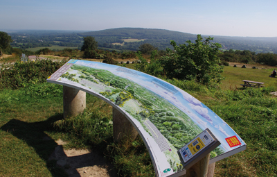 Panorama depuis le sommet du mont Doville. Derrière la table d’orientation, le mont Étenclin, lieu où les « sorciers » de La Haye-du-Puits étaient censés célébrer leurs sabbats infernaux.  (© Stéphane William Gondoin)