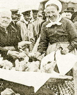 Paysanne choisissant une poule à la foire de La Pernelle au début du XXe siècle. (Coll. Heimdal.)