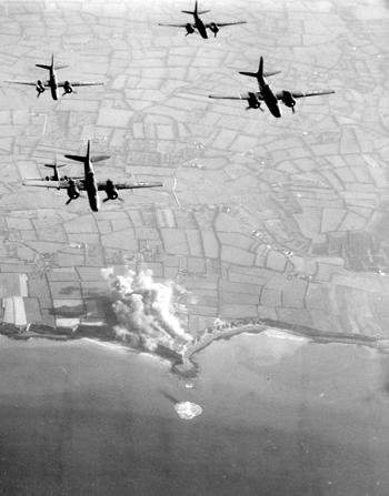 Des bombardiers B-26 Marauder de la 9th US Air Force écrasent les positions allemandes de la pointe du Hoc sous les bombes de gros calibre ; l’assaut des Rangers va pouvoir commencer. (US Air Force)