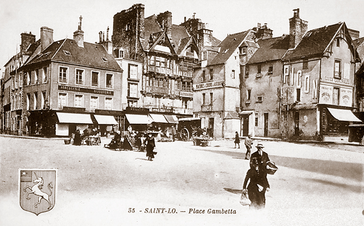 La place Notre-Dame. Nous tournons le dos à l’église et faisons face ici aux maisons qui la bordent. On aperçoit la Maison Dieu en pan de bois, au centre. A gauche s’ouvre la place des Beaux-Regards qui s’achève sur le rempart. (Carte postale © Archives Départementales de la Manche, Saint-Lô.)